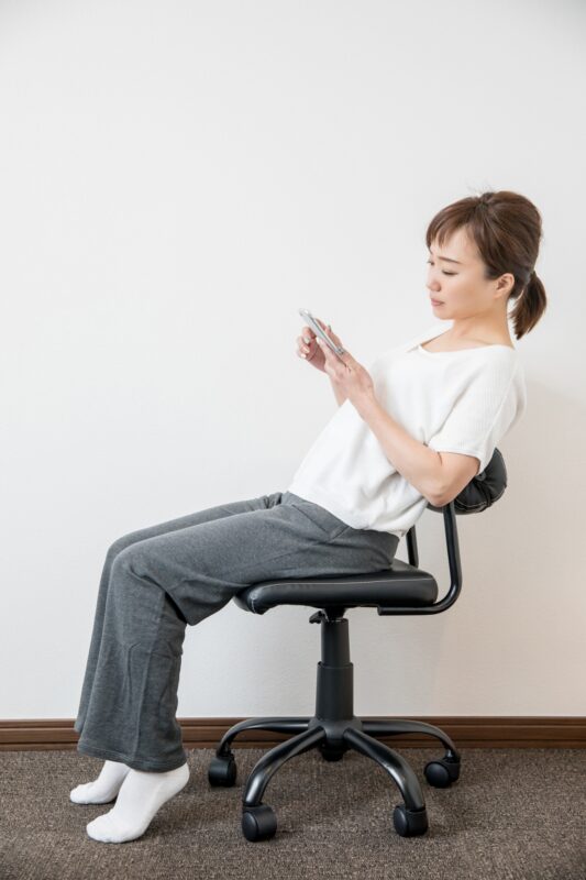 猫背でスマホ操作する女性